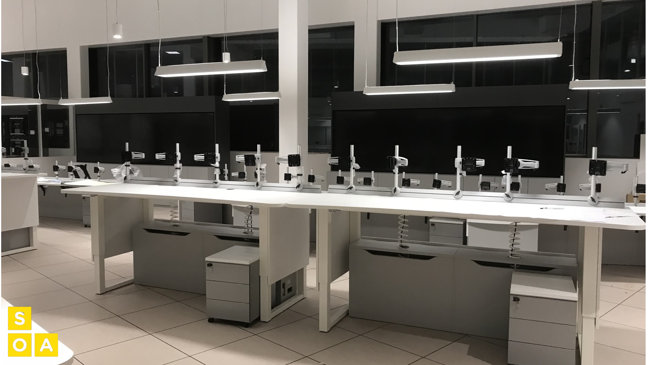 Espace technique équipé de plans de travail et de postes informatiques intégrés, conçu pour la surveillance, la maintenance et les tests des infrastructures du site